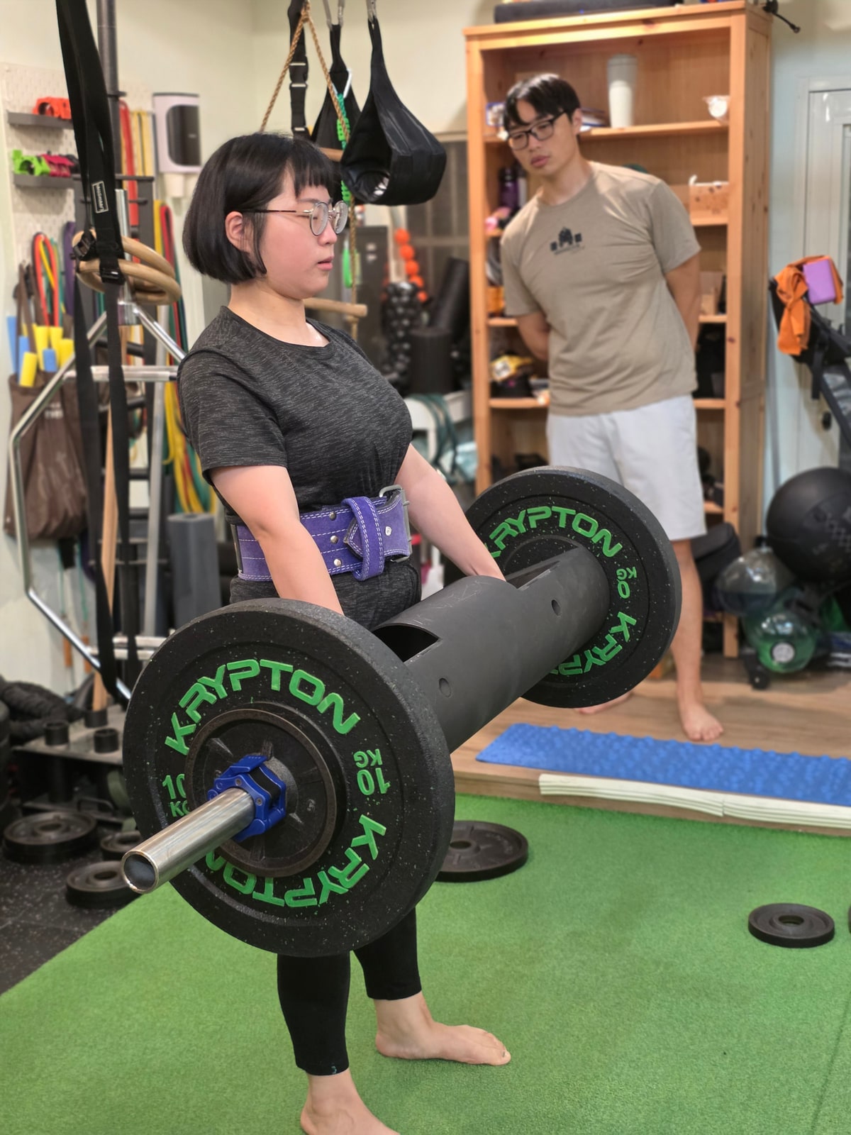 B.S 力線體學員使用負重器材練習，教練在旁觀察動作
